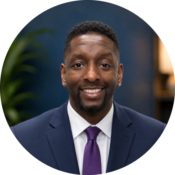 Dr. Farid Johnson smiling in a plaid blazer and navy tie
